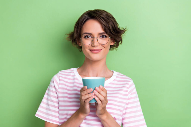 Closeup photo of young adorable attractive cute girl hold cup of coffee wear glasses smart businesswoman looking you isolated on green color background. - Zdjęcie, obraz