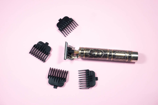 Elektromos fém borotva vagy száraz borotva különböző hosszúságú tartozékokkal. Trimmer vágására és eltávolítására felesleges haj rózsaszín háttér. Stílusos szakáll, templomok. - Fotó, kép