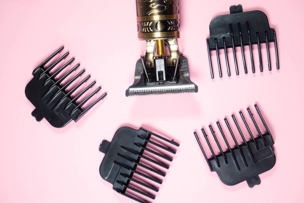 Electric metal razor or dry shaver with set of attachments for different lengths. Trimmer for cutting and removing excess hair on pink background. Styling beard, temples. - Photo, Image