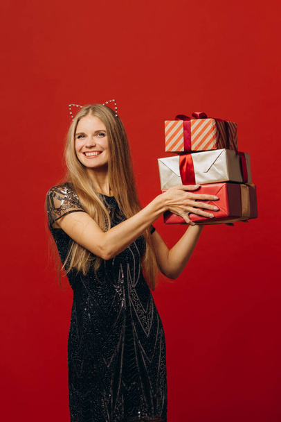 Feliz Navidad: una mujer rubia feliz en un vestido festivo con regalos de Navidad. Retrato - foto de stock - Foto, imagen
