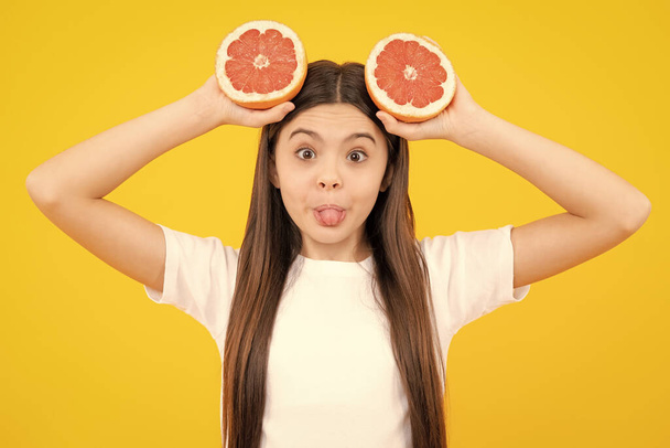 Cara graciosa. Chica adolescente con pomelo. Vitamina y frutas. Niño comiendo naranja - Foto, imagen