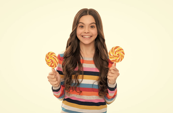 yummy. happy girl hold lollipop isolated on white. lollipop child. kid in colorful sweater hold lollypop. sugar candy on stick. caramel candy shop. childhood happiness. teen dental care. sweet tooth. - Fotografie, Obrázek