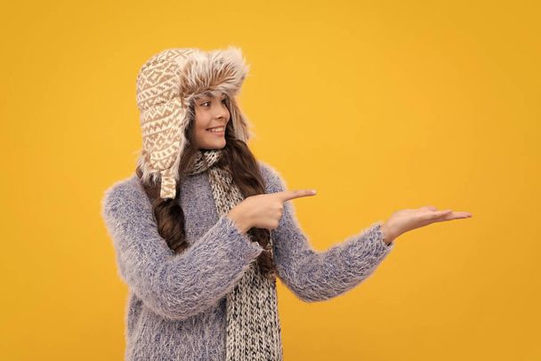 Modern teenage girl 12, 13, 14 year old wearing sweater and knitted hat on isolated yellow background. Happy face, positive and smiling emotions of teenager girl - Foto, immagini