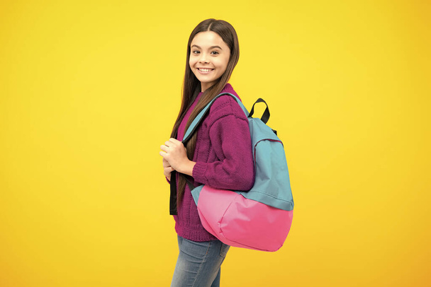Шкільна дівчина в шкільній формі зі шкільною сумкою. Школярка підліток тримає рюкзак на жовтому ізольованому фоні
 - Фото, зображення
