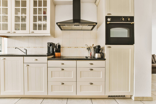una cucina con armadi bianchi e ripiani neri sui banchi in questa foto è scattata dall'interno - Foto, immagini