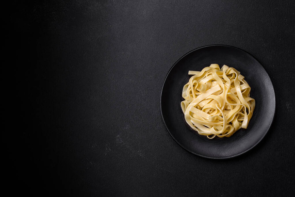 Вкусная свежая паста с песто-соусом и морепродуктами на черной тарелке на темном бетонном фоне - Фото, изображение