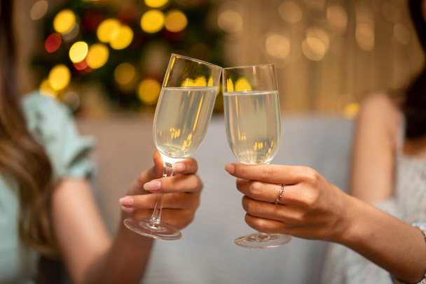 Jovens pessoas bonitas sentadas no sofá e taça de champanhe a brindar com felicidade enquanto comemoram na festa de ano novo em casa. - Foto, Imagem