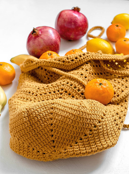 Crochet yellow mesh bag with fresh organic fruits on a yellow background. Eco friendly shoping and healthy eating concept. - Zdjęcie, obraz