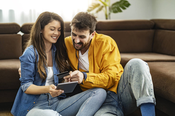 Porträt eines jungen Paares mit digitalem Tablet und Kreditkarte beim Online-Kauf. Online-Shopping-Konzept. - Foto, Bild