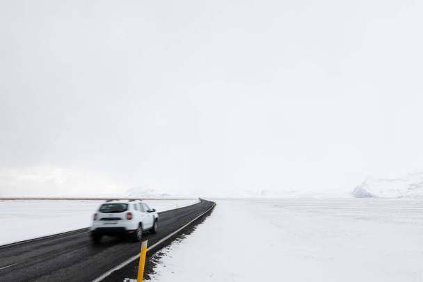 Car Driving On Road LEading Through the Frozen Snowy Landscape of Southern Iceland in Winter - Zdjęcie, obraz