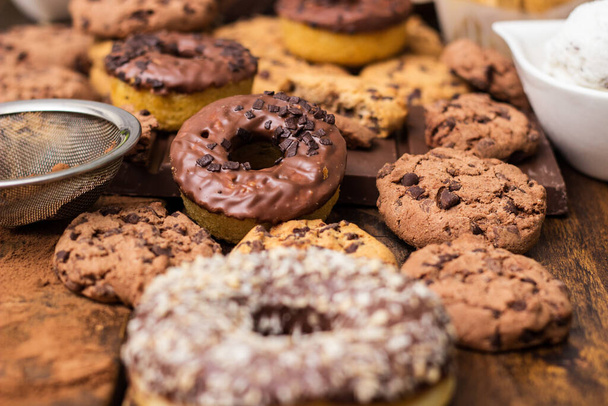 アイスクリーム、ドーナツ、チョコレートチップクッキーを含む甘いテーブル - 写真・画像