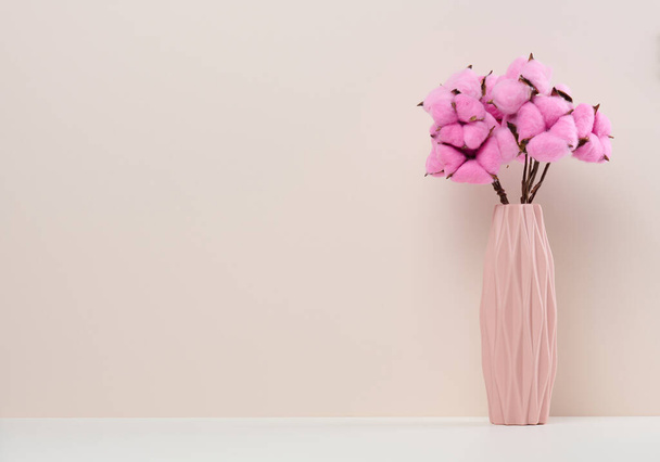 Pink ceramic vase with rose cotton bouquet on white table, copy space - Photo, Image