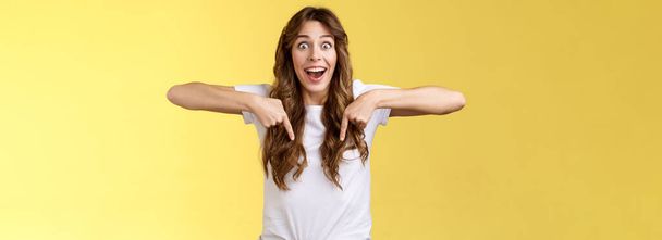 Tempting astonished impressed excited lively girl fan react stunned lose speech fascinated pointing down thrilled stare camera admiration surprise full disbelief stand yellow background. - Photo, Image