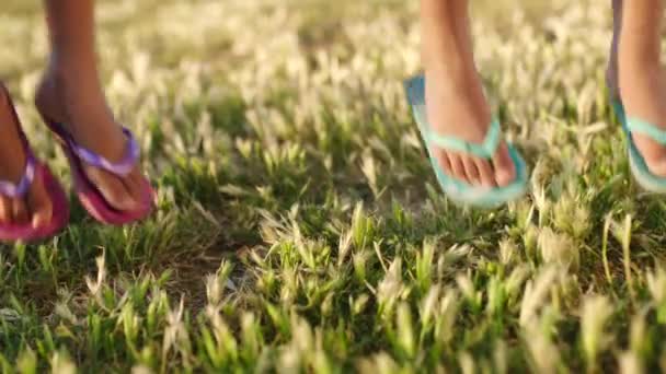 Kinderen, zomer en voeten springen samen op gras met teenslippers voor vakantie, plezier en jeugd. Vrijheid, vakantie en kinderen springen op het gazon met geluk in de zon op de natuurwandeling - Video