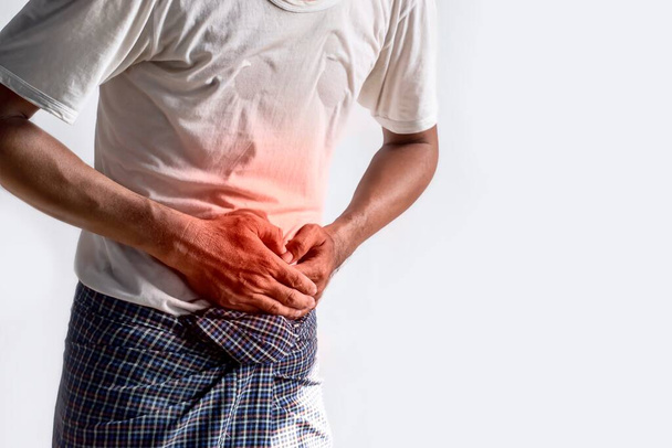 Asian young man suffering from upper abdominal pain. It can be caused by stomach ache, enteritis, colitis, appendicitis, hepatitis, pancreatitis, food poisoning, irritable bowel syndrome, etc. - Photo, Image