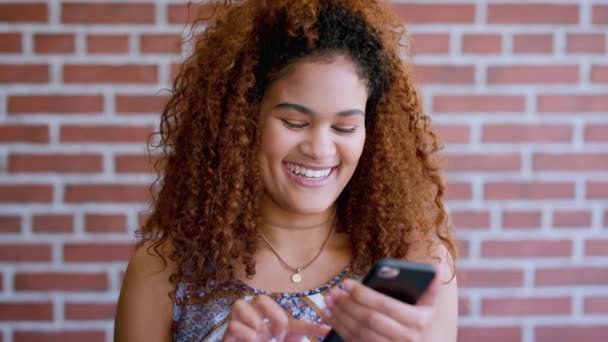 Teléfono, redes sociales y sonrisa con una estudiante mujer negra en la universidad o la universidad contra un fondo de pared de ladrillo. Móvil, comunicación y educación con una alumna feliz en el campus para aprender. - Metraje, vídeo