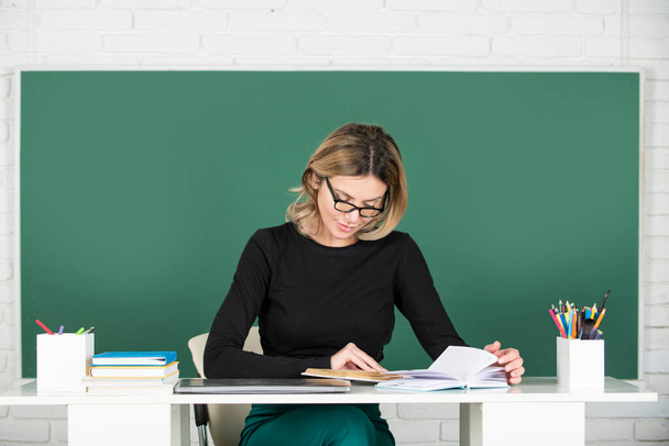 Portrait of female teacher teaching in classroom on blackboard. Education and tutoring concept - Foto, afbeelding