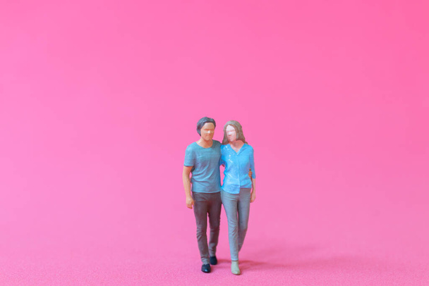 Personas en miniatura hombre y mujer en tela casual de pie juntos sobre fondo rosa, el concepto del día de San Valentín - Foto, imagen