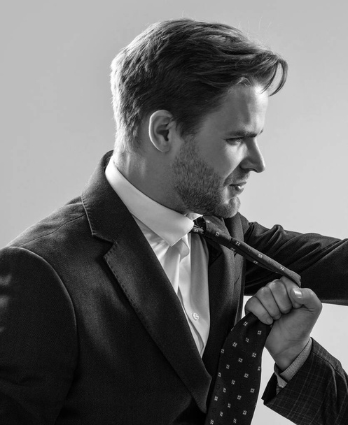 Gerente de hombre profesional en traje siendo tirado por la corbata durante el conflicto laboral fondo gris, conflictivo. - Foto, imagen
