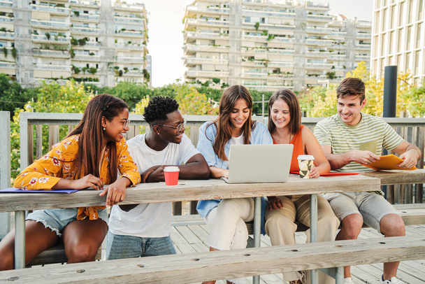 Lächelnde multirassische Studenten, die im Internet suchen und lustige Videos auf dem Universitätscampus ansehen. Glückliche und positive Gruppe junger Freunde, die lachen und Inhalte in den sozialen Medien online teilen - Foto, Bild