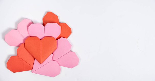 Origami για την Ημέρα του Αγίου Βαλεντίνου - καρδιές από χαρτί σε λευκό φόντο το κάνετε μόνοι σας. - Φωτογραφία, εικόνα