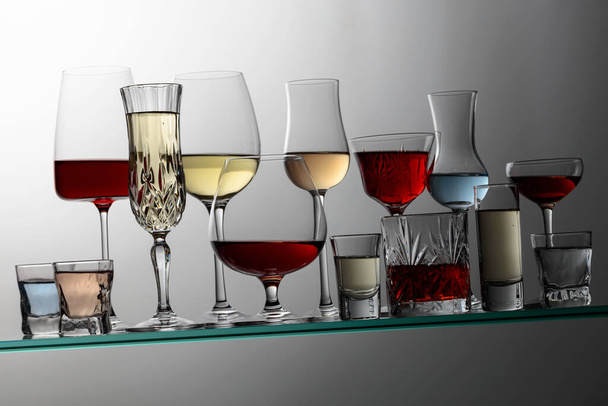 Various alcoholic drinks in a bar on a tilted glass shelf. - Foto, Imagem