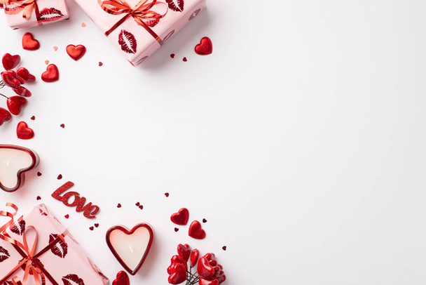 Concepto de San Valentín. Foto vista superior de cajas de regalo en papel de regalo con labios de beso patrón corazones rojos confeti inscripción amor y velas sobre fondo blanco aislado con copyspace - Foto, imagen