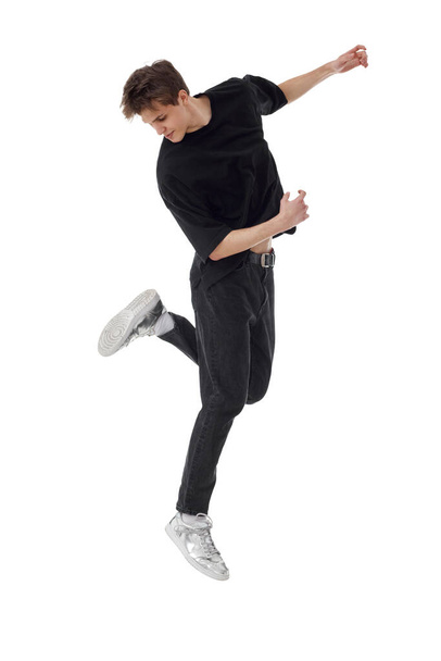 young man in black t-shirt jumping high isolated on white background. Full length - 写真・画像