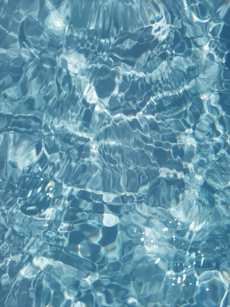 Defocus elmosódott átlátszó kék színű tiszta, nyugodt vízfelület textúra fröccsenések és buborékok. Trendi elvont természet háttér. Vízhullámok a napfényben fénymásolási hellyel. Kék akvarell ragyog - Fotó, kép