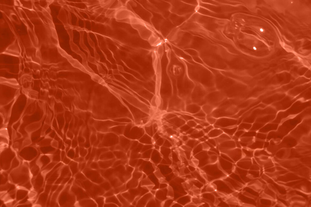 Defocus elmosódott átlátszó piros narancs színű tiszta, nyugodt vízfelület textúra fröccsenések és buborékok. Trendi elvont természet háttér. Vízhullámok a napfényben fénymásolási hellyel. Piros narancs akvarell ragyog - Fotó, kép