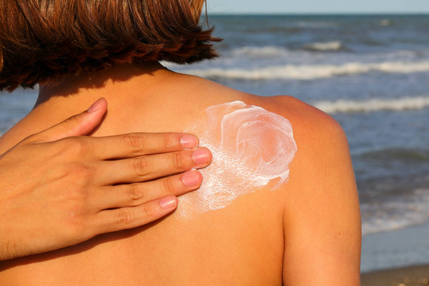 hand lovingly spreading skin protection sunscreen on little girl back in summer - Photo, Image