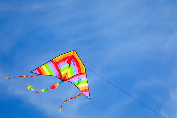 velký duha barevný drak létání vysoko na modré obloze s některými bílými mraky - Fotografie, Obrázek