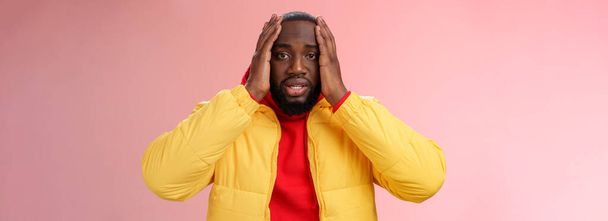 Shocked upset african-american bearded guy feel regret stunned hear terrible news hold hands head widen eyes stupor standing speechless troubled, look perplexed terribly sad, pink background. - Foto, Imagen
