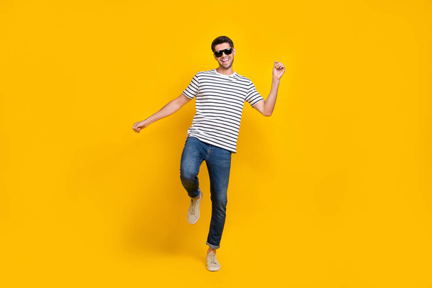 Full length photo of funky cheerful man wear white t-shirt dark glasses having fun dancing isolated yellow color background. - Zdjęcie, obraz