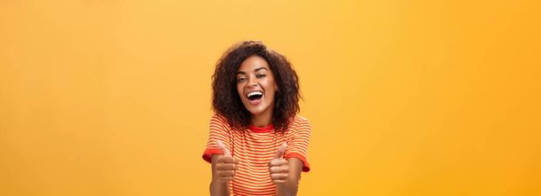 Woman surely knows how boost mood. Portrait of friendly-looking stylish and outgoing african american girlfriend with curly hairstyle showing thumbs up in like and approval agreeing to friend idea. - Foto, Imagem