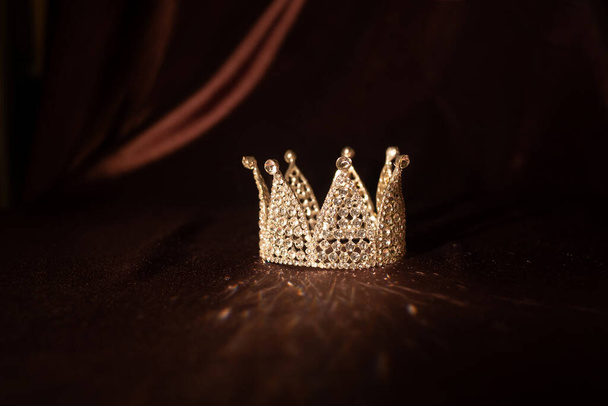 Little crown on brown satin, silk background. Fairytale - Photo, Image