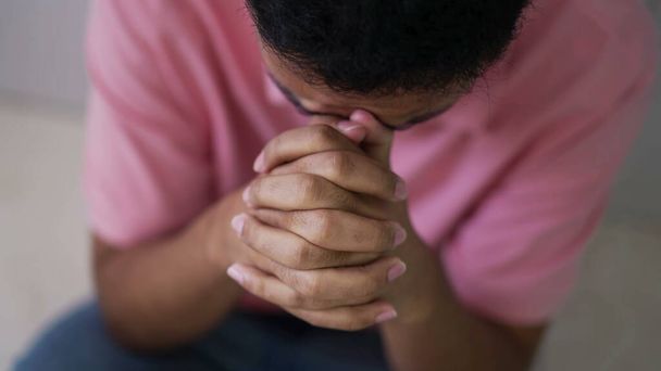 Hopeful young man in prayer. Closeup person hands praying to God. Spiritual and religious individual having FAITH - Photo, Image