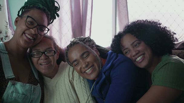 Mulheres afro-americanas felizes abraçando juntas. Brasileiros latino-americanos abraçam em casa sofá da sala de estar - Foto, Imagem
