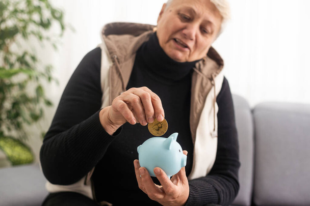 Pénzgazdálkodási koncepció. Egy idős nő egy malacperselyt tart a kezében.. - Fotó, kép