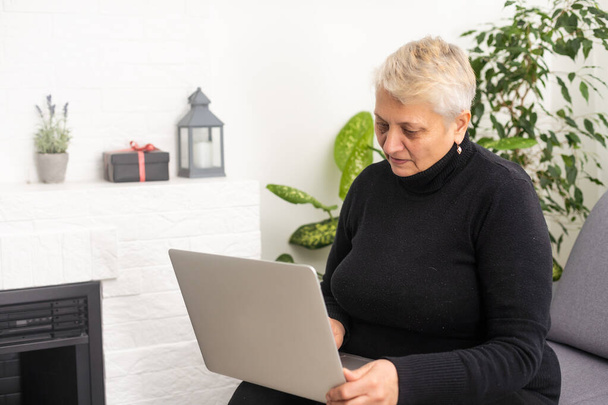 Előnézet koncentrált kellemes érett idős nő nézi a számítógép képernyőjén. Boldog középkorú hölgy web szörfözés információk, rendelés élelmiszer online, chat a szociális hálózatok, játék játék. - Fotó, kép