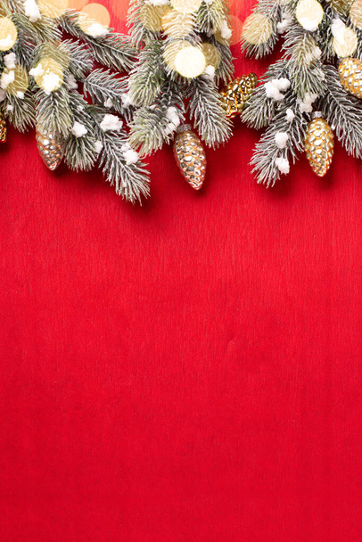 Frame from branches of fir tree and decorative golden cones on  red paper textured background. Top view. Christmas, New Tear holidays concept.  Place for text - Valokuva, kuva