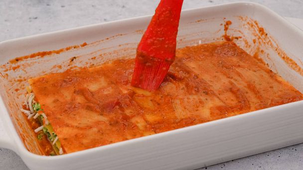 Stel de lasagne samen. Topping laatste laag lasagne met marinara saus. Recept van spinazie lasagne - Foto, afbeelding