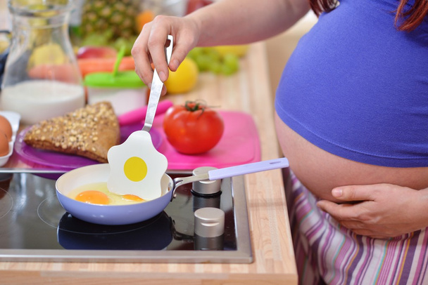 Pregnant woman prepares meal - Фото, изображение