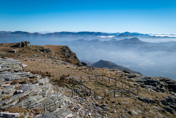 Гора Ла-Рюн в Стране Басков с деревянным забором для животных и туманом на заднем плане над горами  - Фото, изображение