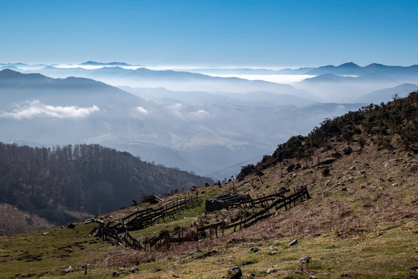Гора Ла - Рун у Країні Басків з дерев "яним парканом для тварин і туманом на задньому плані через гори.  - Фото, зображення