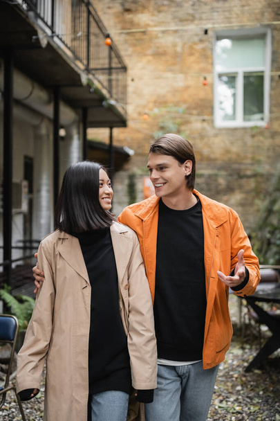 Positivo homem falando com elegante asiático namorada no exterior café  - Foto, Imagem