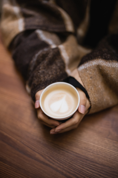 Top view of woman in blanket holding cappuccino in outdoor cafe  - Photo, Image