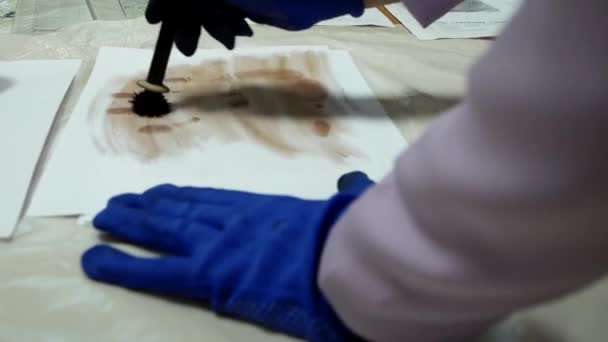 A crime scene investigator dusts for fingerprints with a forensic brush to solve a mystery. Dusting For Fingerprint Evidence. Criminologist police chemist takes palm prints from a sheet of paper. - Πλάνα, βίντεο