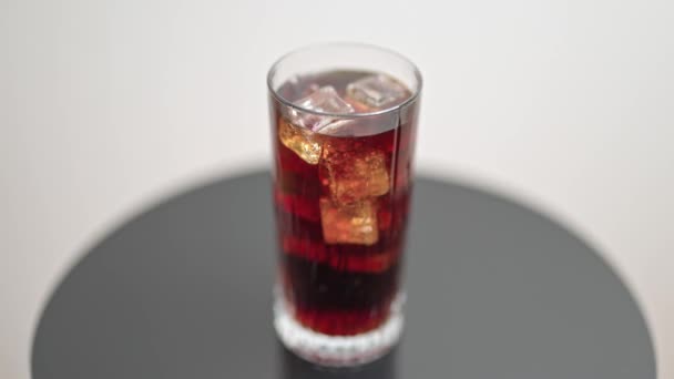 Vista da vicino della bevanda di soda versata nel bicchiere con cubetti di ghiaccio che vorticano sullo sfondo. - Filmati, video