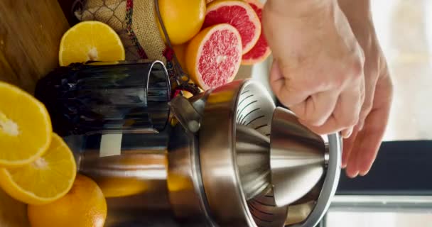 Le mani maschili spremono il succo d'arancia su uno spremiagrumi. Vista da vicino. Filmati 4k verticali. 60 fps. - Filmati, video